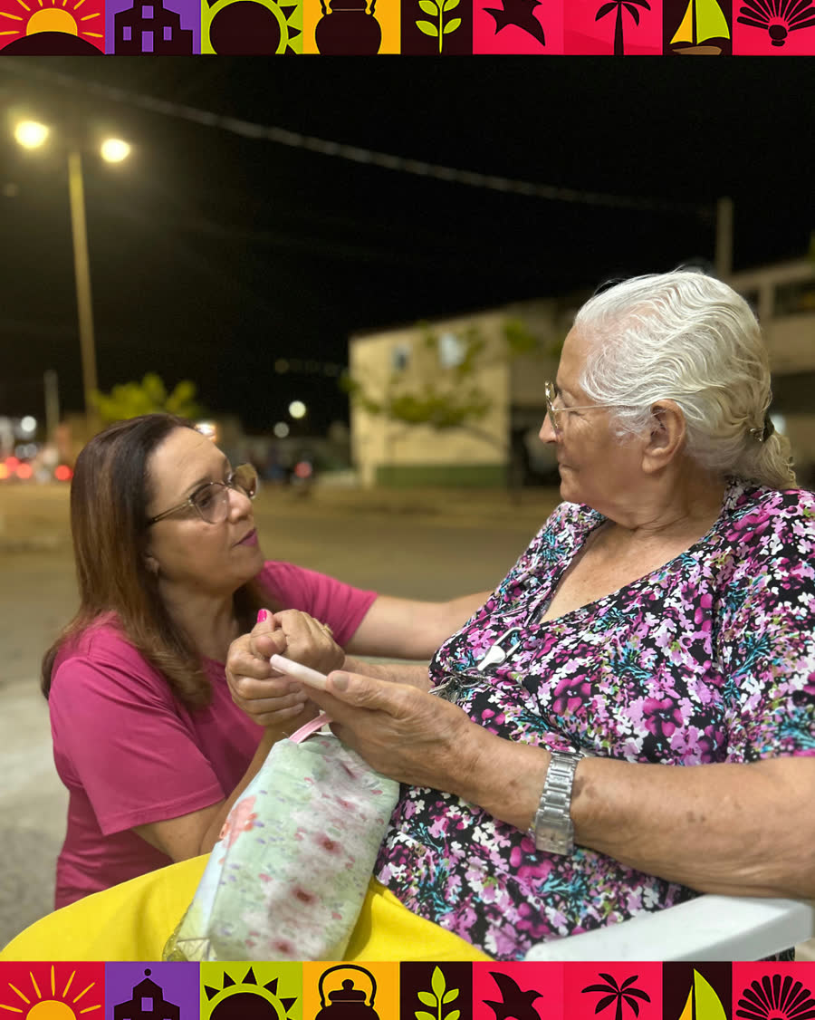 Cristiane conversa com uma mulher sentada em uma praça