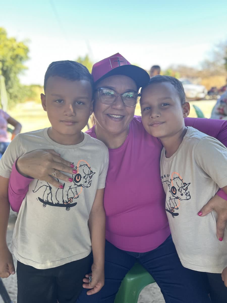 Cristiane ao lado de duas crianças durante uma atividade comunitária